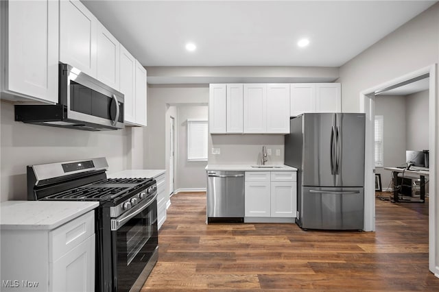 kitchen with appliances with stainless steel finishes, dark wood finished floors, white cabinets, and a sink