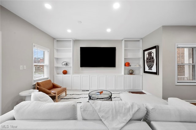 living area featuring baseboards, built in shelves, and recessed lighting