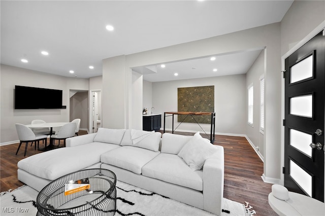 living area with baseboards, wood finished floors, and recessed lighting