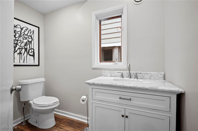 bathroom featuring baseboards, vanity, toilet, and wood finished floors