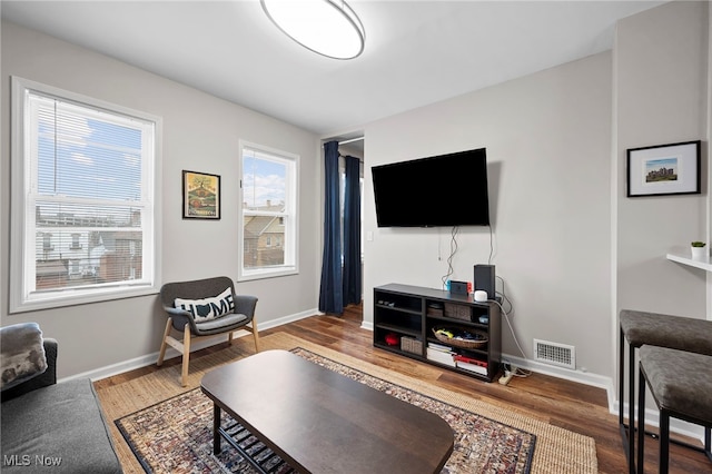 living room featuring baseboards, visible vents, and wood finished floors