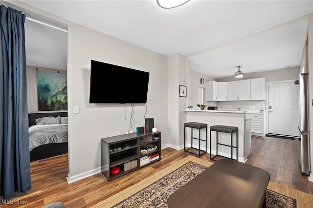 living room featuring baseboards, a ceiling fan, and wood finished floors