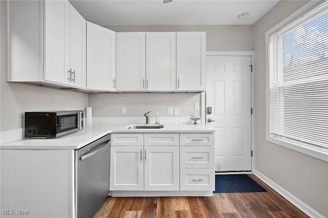 kitchen featuring wood finished floors, a sink, white cabinetry, light countertops, and appliances with stainless steel finishes