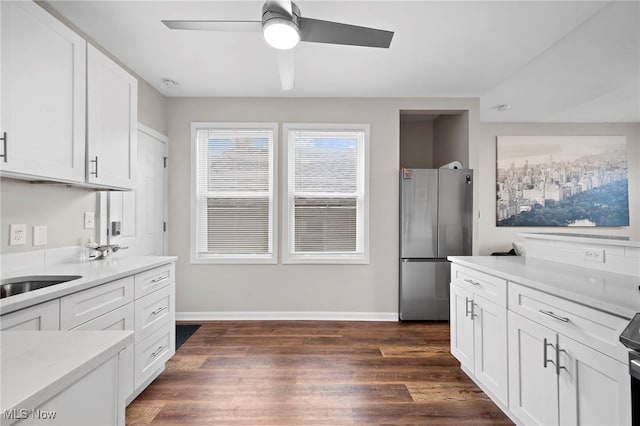 kitchen featuring white cabinets, dark wood finished floors, light countertops, and freestanding refrigerator