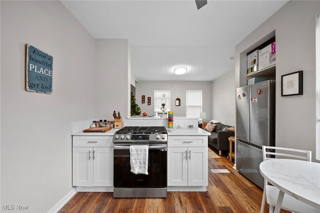 kitchen featuring baseboards, dark wood-style floors, appliances with stainless steel finishes, light countertops, and white cabinetry