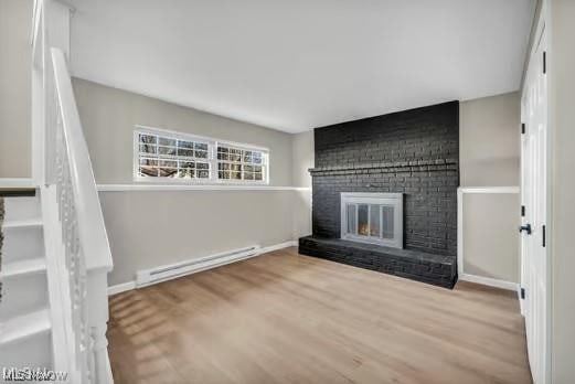 unfurnished living room with a brick fireplace, a baseboard radiator, baseboards, and wood finished floors