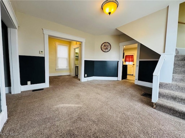 unfurnished living room with carpet floors, visible vents, stairway, and baseboards