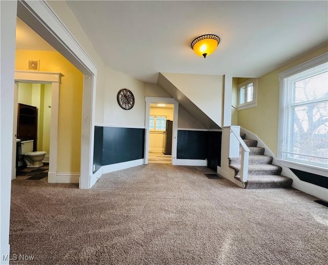 unfurnished living room with carpet, stairs, and baseboards