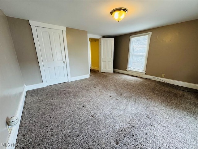 unfurnished bedroom featuring carpet floors, baseboards, and a closet