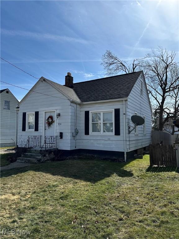 bungalow-style house featuring roof with shingles, a front lawn, a chimney, and fence