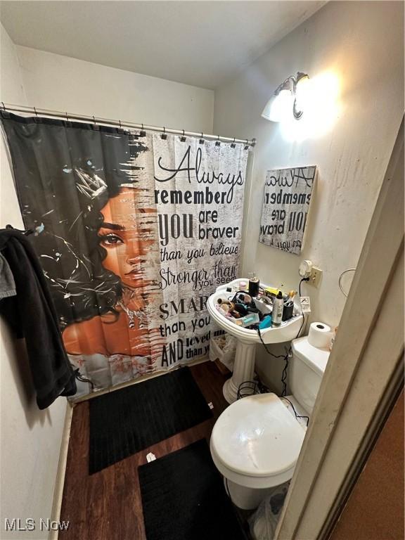 bathroom featuring a shower with shower curtain, wood finished floors, and toilet