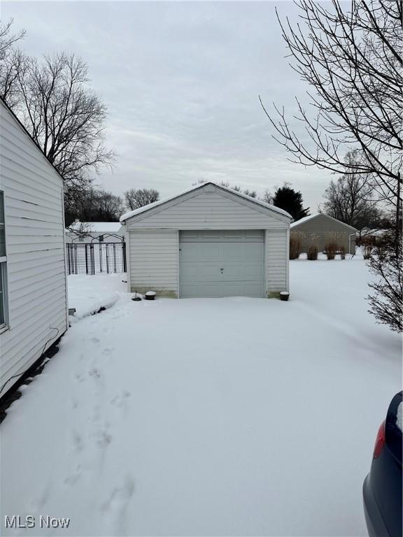 snow covered garage with a detached garage