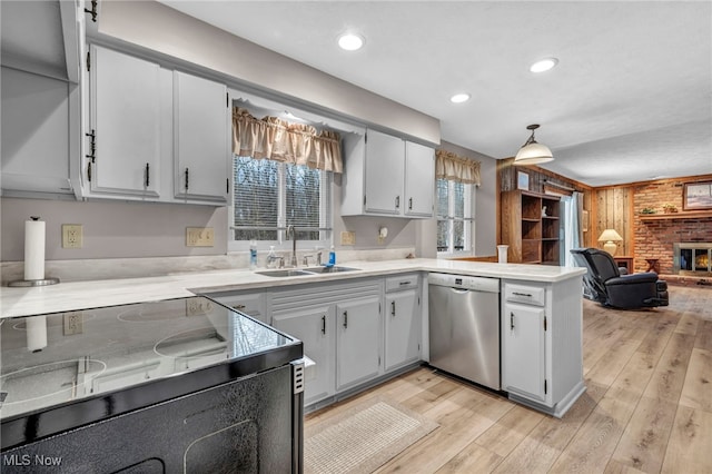 kitchen featuring a peninsula, electric range, a sink, open floor plan, and stainless steel dishwasher