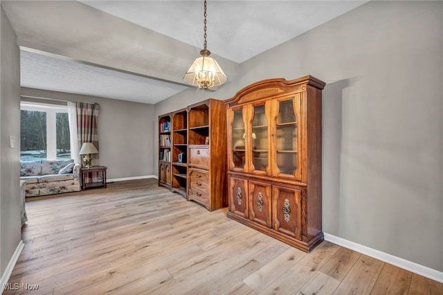 interior space with light wood-style floors, baseboards, and an inviting chandelier