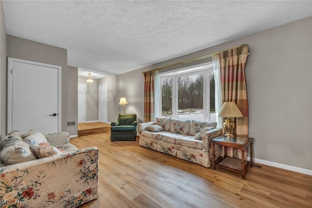 living area featuring a textured ceiling, hardwood / wood-style floors, and baseboards