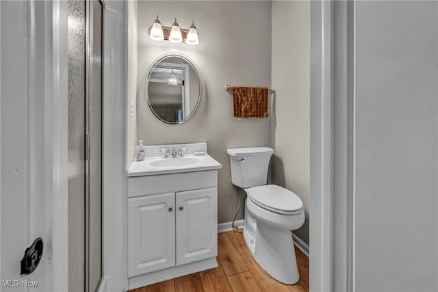 bathroom featuring baseboards, vanity, toilet, and wood finished floors