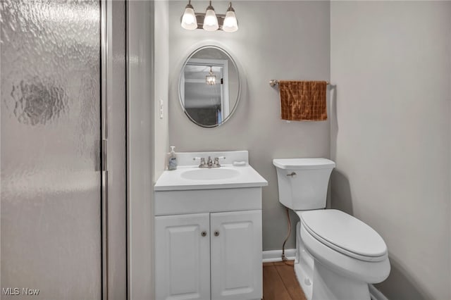 bathroom featuring baseboards, vanity, toilet, and wood finished floors