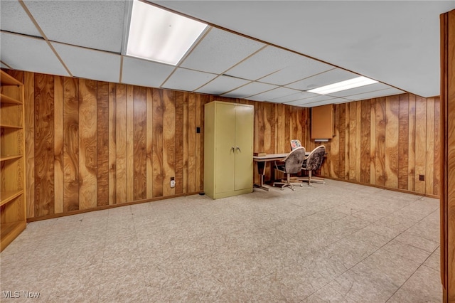 unfurnished office featuring a drop ceiling, wood walls, baseboards, and tile patterned floors