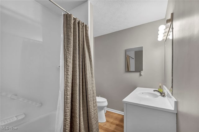 bathroom featuring baseboards, toilet, wood finished floors, a textured ceiling, and vanity