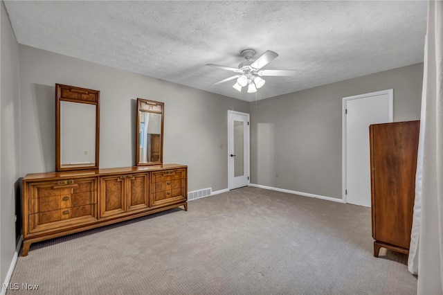 unfurnished bedroom with light carpet, a textured ceiling, visible vents, and baseboards