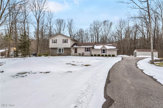 tri-level home with a garage, an outbuilding, and stone siding