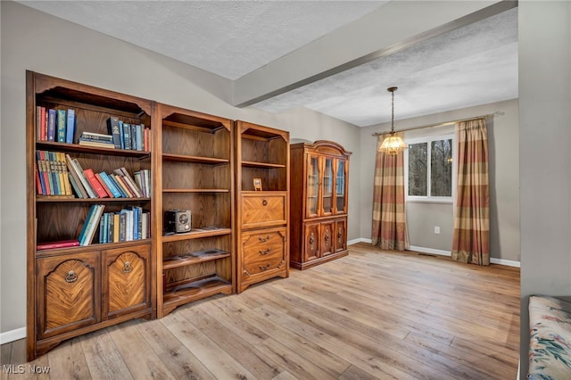 sitting room with light wood-style flooring, baseboards, and a textured ceiling