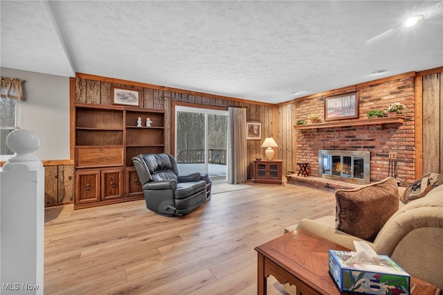 living area with plenty of natural light, light wood-type flooring, a fireplace, and a textured ceiling