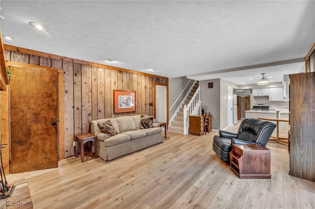 living room with light wood-style flooring, a textured ceiling, and stairs