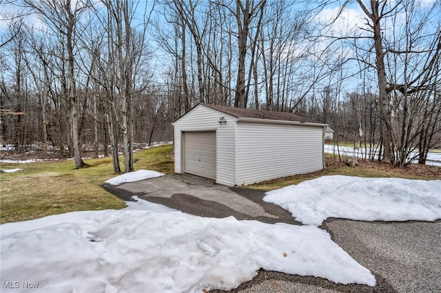 snow covered garage with a garage and driveway