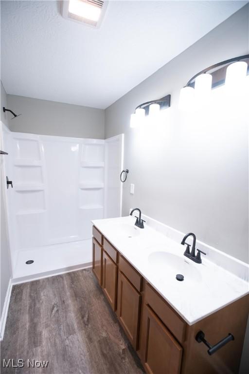 full bathroom with a shower, a sink, and wood finished floors