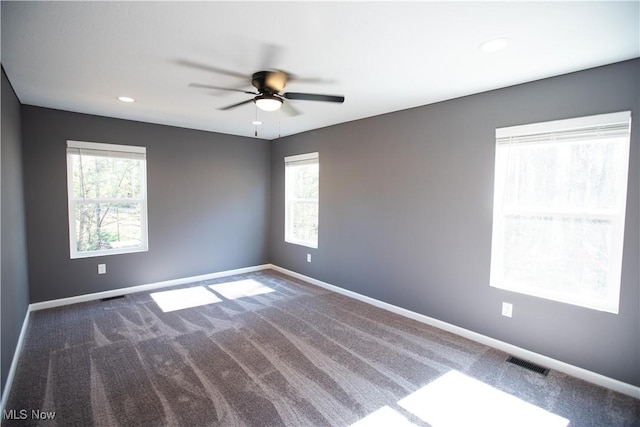 carpeted empty room with a healthy amount of sunlight, visible vents, and baseboards