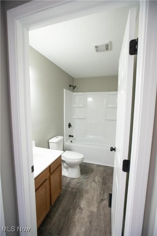 bathroom with visible vents, toilet, vanity, wood finished floors, and shower / bathtub combination