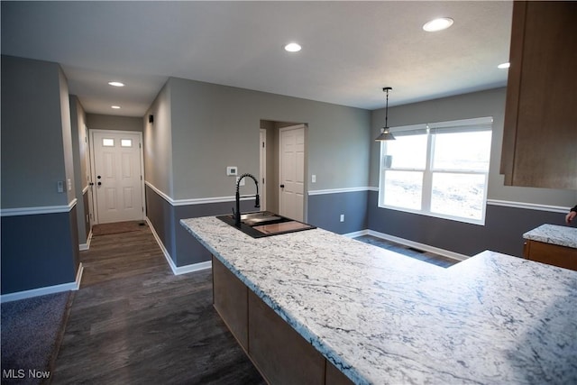 kitchen featuring dark wood-style floors, recessed lighting, hanging light fixtures, a sink, and baseboards