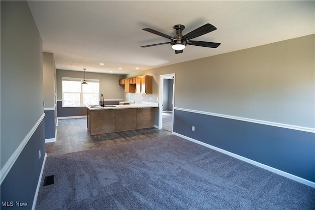 kitchen with a sink, visible vents, baseboards, open floor plan, and light countertops