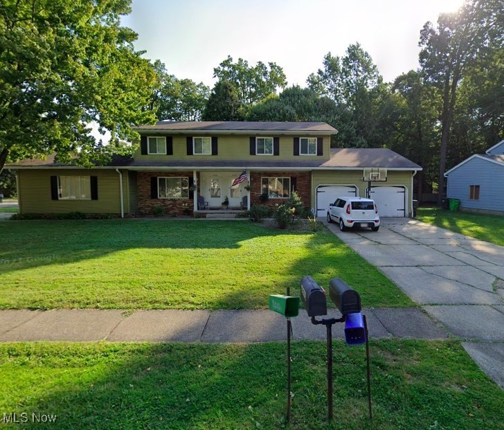 traditional-style home featuring brick siding, a porch, concrete driveway, an attached garage, and a front yard