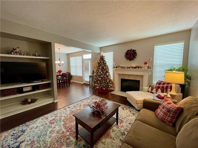 living room with a textured ceiling, a glass covered fireplace, wood finished floors, and a notable chandelier