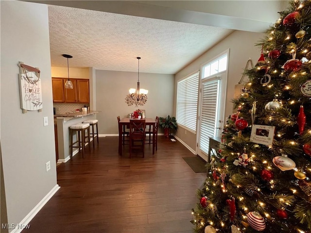 dining room featuring a textured ceiling, baseboards, and dark wood-type flooring