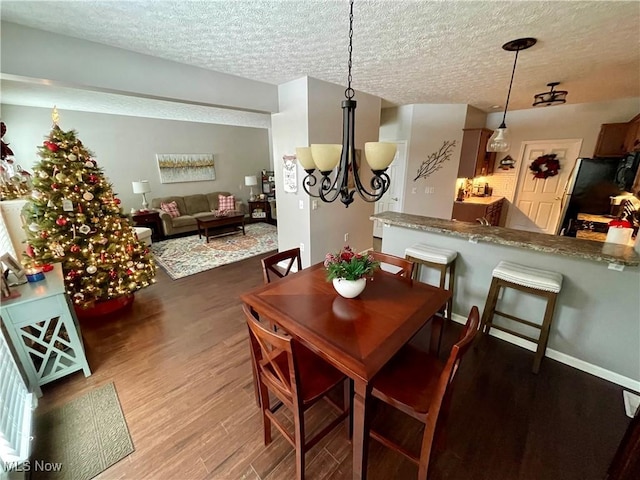 dining space featuring baseboards, a textured ceiling, a chandelier, and wood finished floors