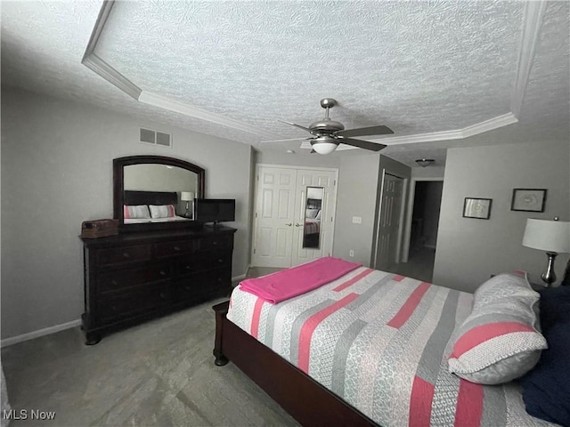 bedroom featuring a textured ceiling, visible vents, and a tray ceiling