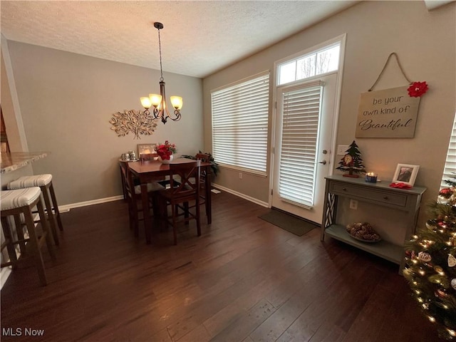 dining space featuring dark wood-style floors, baseboards, a textured ceiling, and an inviting chandelier