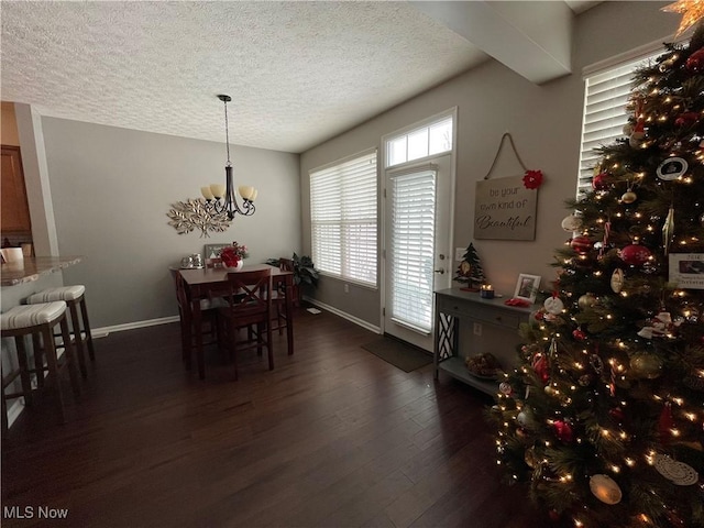 dining area featuring an inviting chandelier, baseboards, dark wood finished floors, and a textured ceiling