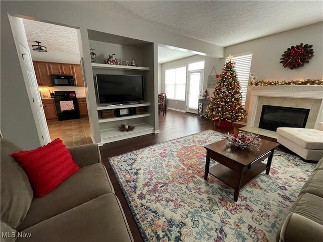 living room featuring a textured ceiling, a fireplace, and wood finished floors