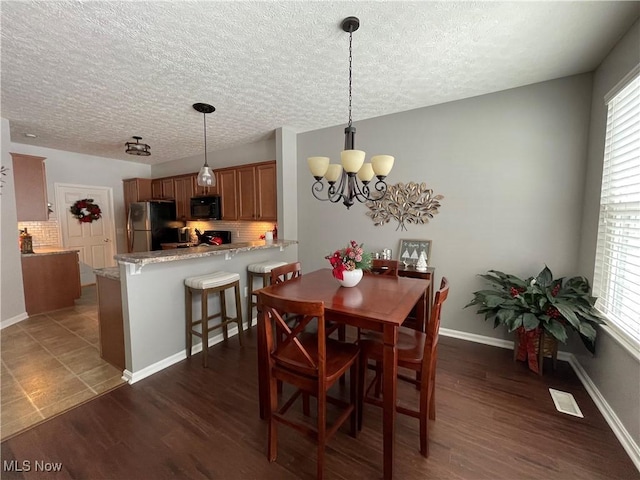 dining room featuring baseboards, dark wood-type flooring, a wealth of natural light, and a notable chandelier