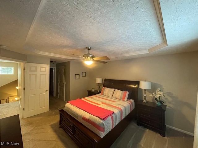 bedroom with a tray ceiling, light carpet, and a textured ceiling