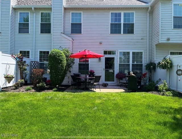 back of property with a patio, a lawn, a chimney, and a fenced backyard