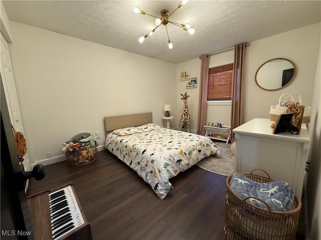 bedroom with a textured ceiling, dark wood-type flooring, and an inviting chandelier