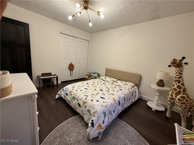 bedroom featuring a textured ceiling, a chandelier, baseboards, a closet, and dark wood finished floors