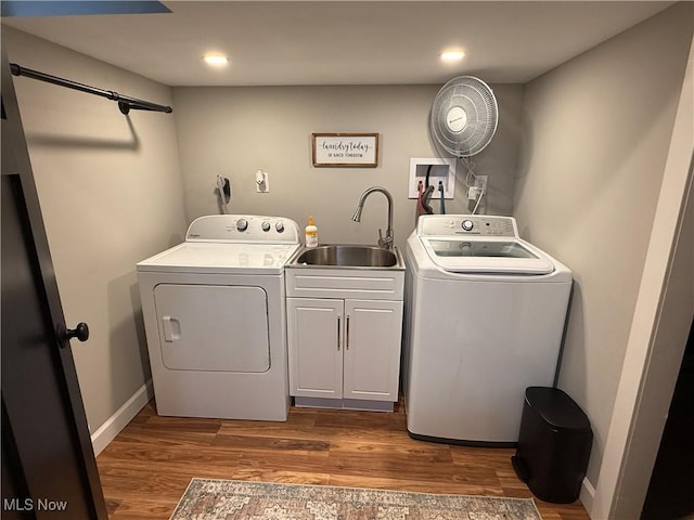 washroom with cabinet space, washer and dryer, dark wood finished floors, and a sink