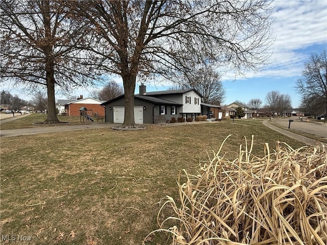 view of side of property with a garage, driveway, a yard, and a chimney