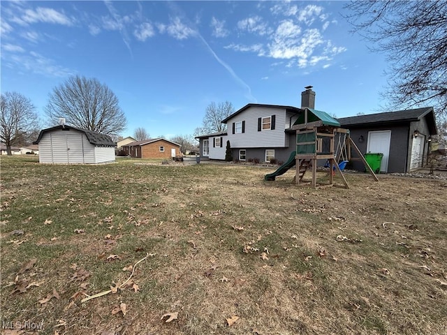 view of yard with an attached garage, a shed, a playground, and an outbuilding